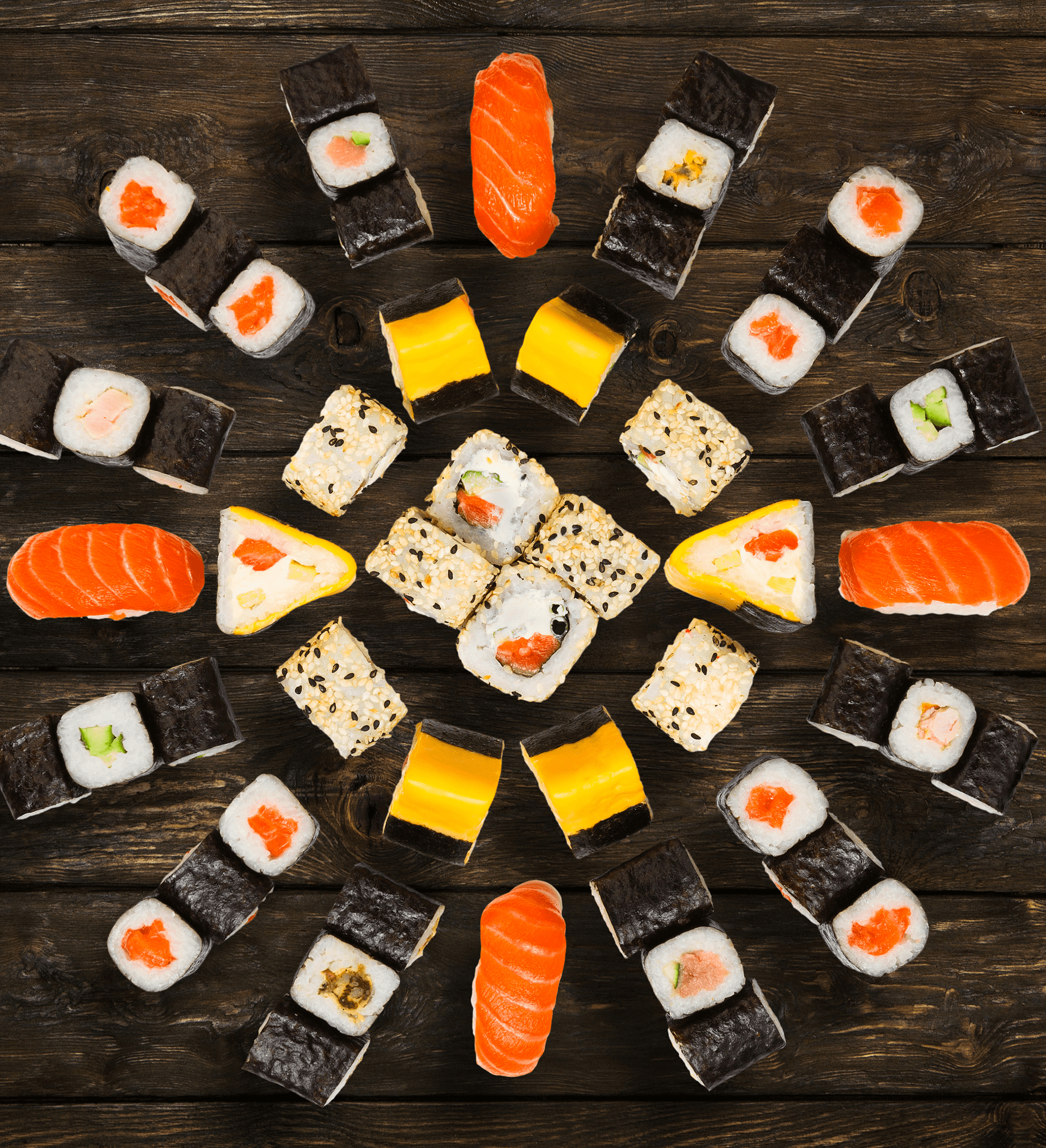 Eine kreisförmig angerichtete Sushi-Platte auf dunklem Holz, von oben fotografiert.