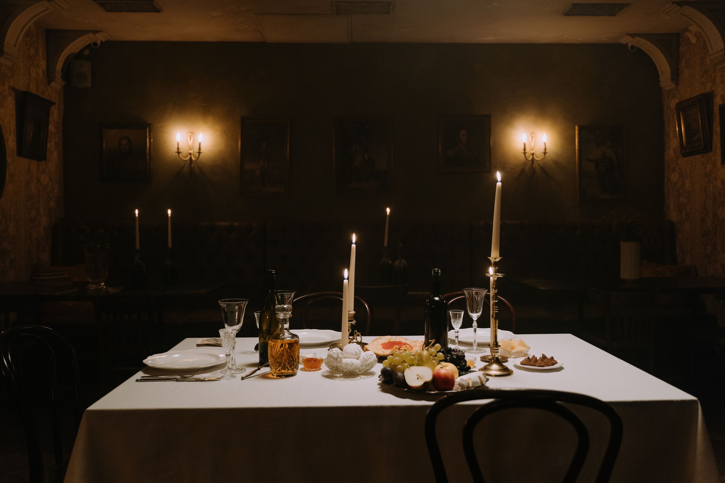 Dunkler Speisesaal mit einem gedeckten Tisch und brennenden Kerzen.